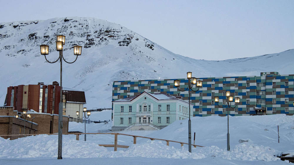 Mehrere Gebäude in Barentsburg vor verschneiter Schneekulisse