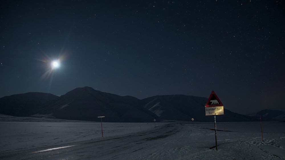 Das Eisbärenschild bei Nacht mit Blick auf das Adventdalen
