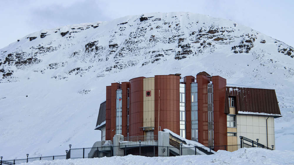 Building in Barensburg in front of a snow-covered mountain