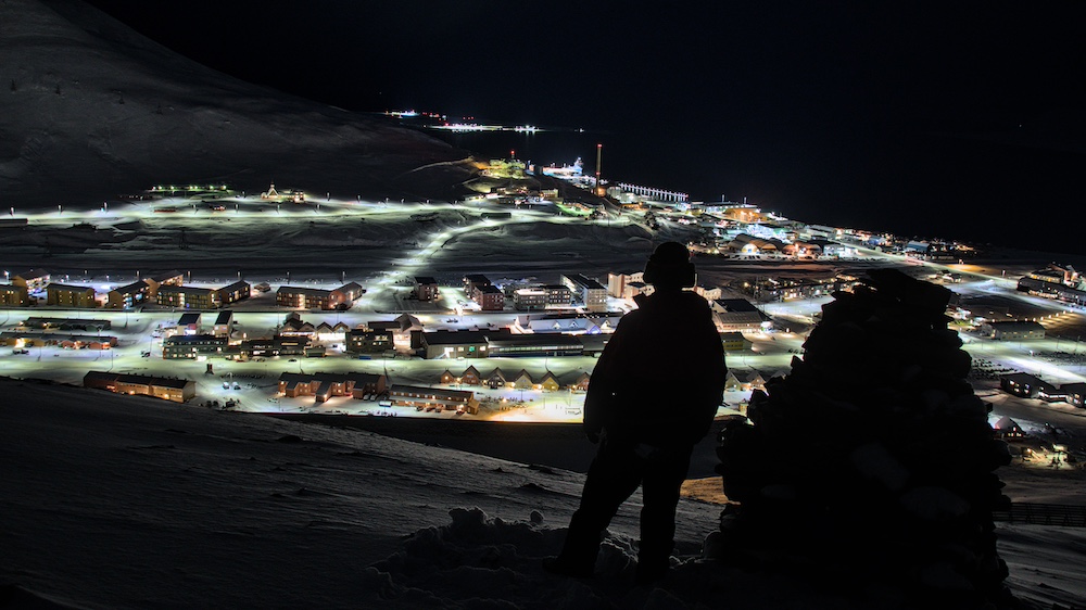 Eine Person blickt auf Longyearbyen bei Nacht
