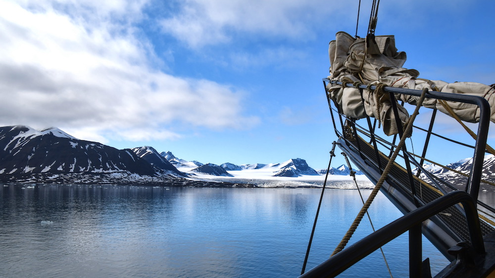 The bow of the sailing ship Meander in front of a glacier