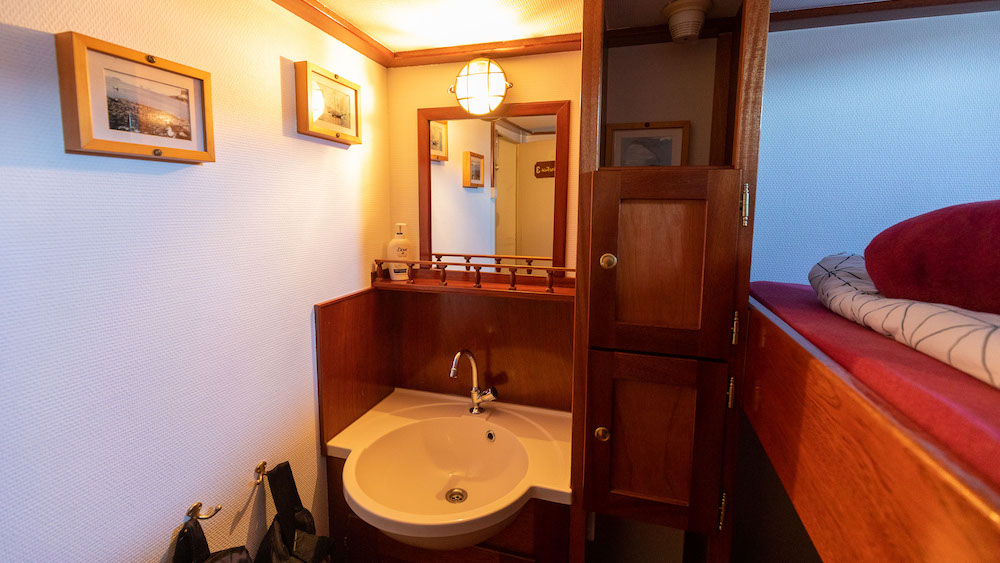 A room with bunk bed and washbasin on the SV Meander