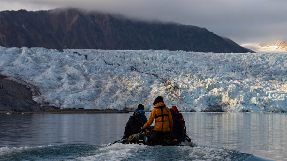 Several people in an inflatable boat on their way to a glacier