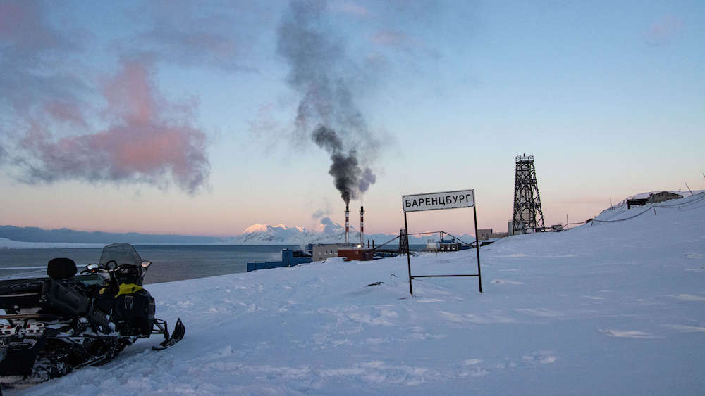 Ortsschild Barentsburg mit Schneemobil