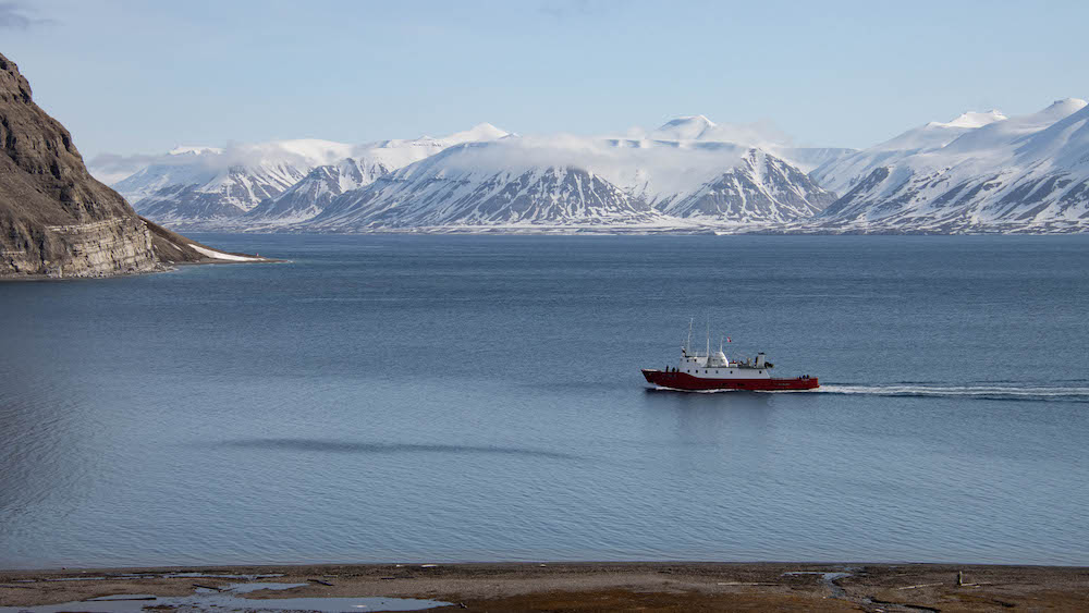 A ship sailing through a fjord on Svalbard