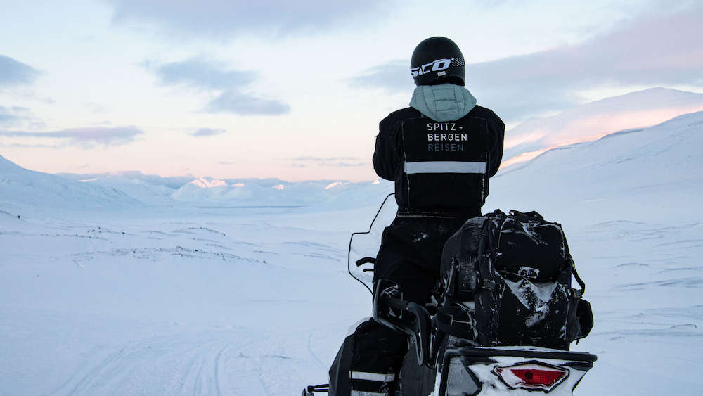 Person steht auf Schneemobil auf Spitzbergen